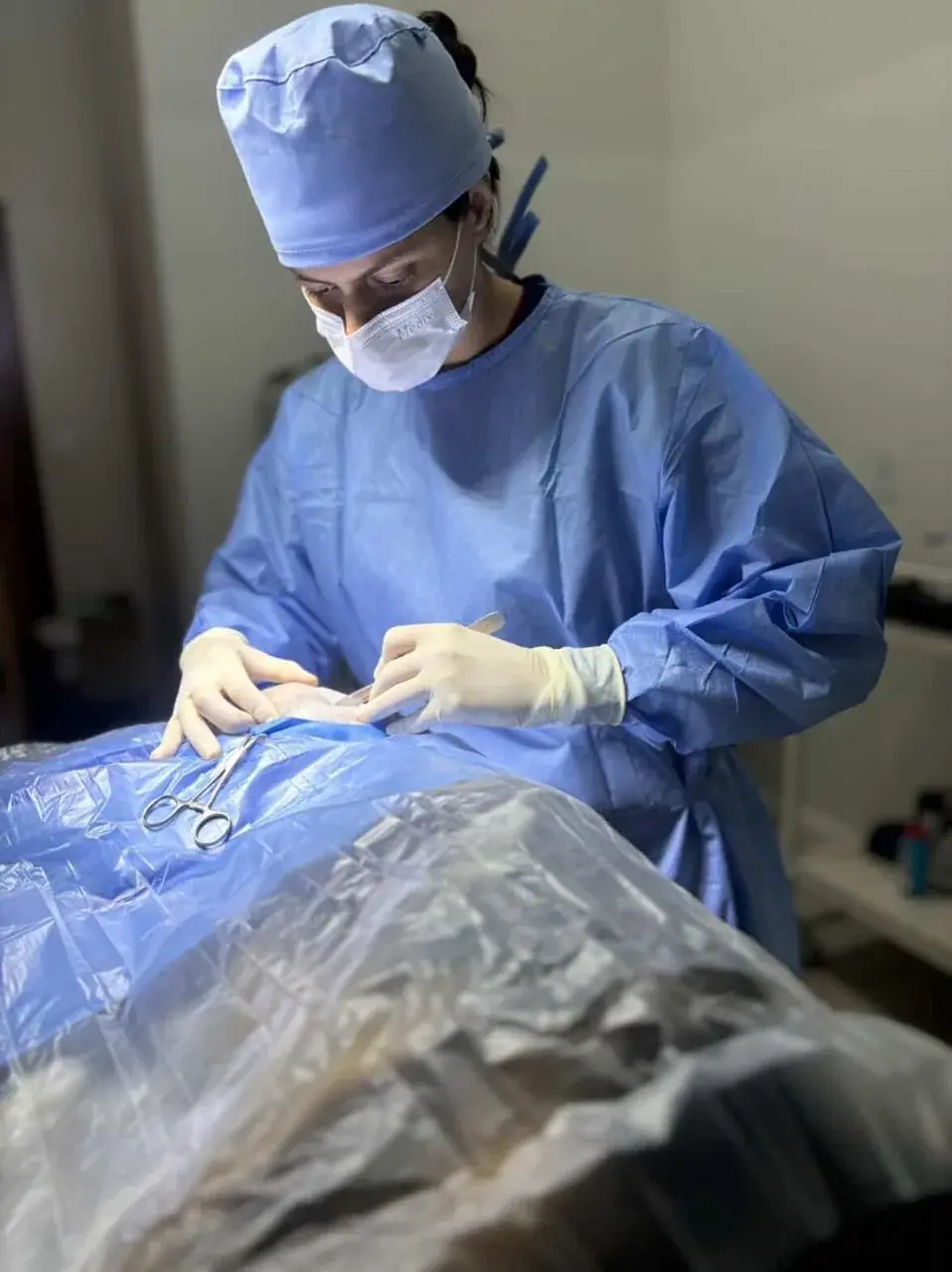 Dra. Mariana Neves paramentada com touca, máscara e capote durante uma cirurgia