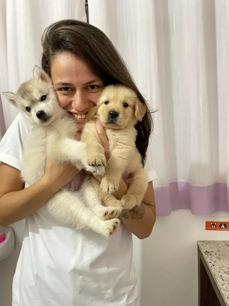 Dra. Mariana Neves com dois filhotes no colo, sorrindo