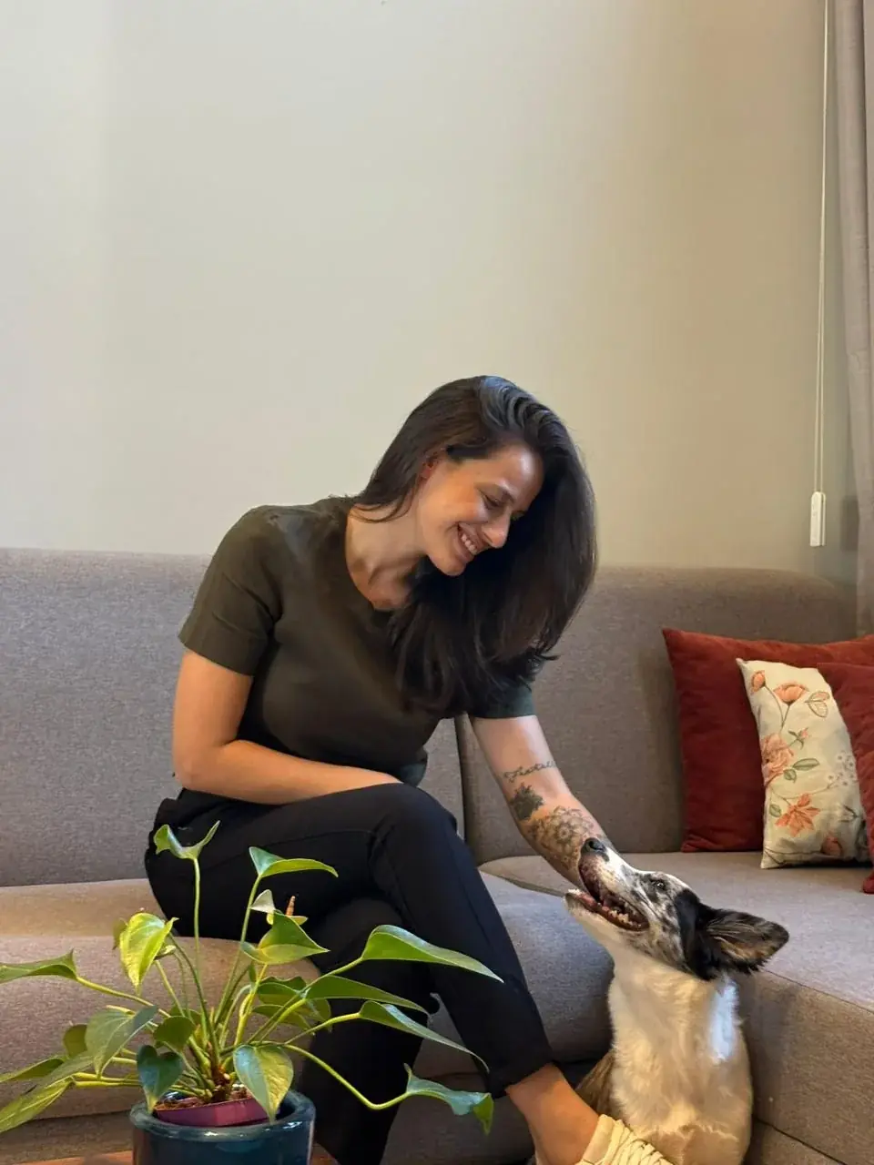 Dra. Mariana Neves sentada no sofá fazendo carinho em um cachorro